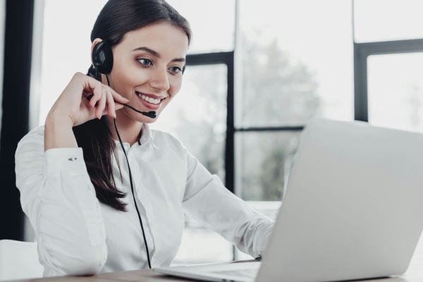 Frau telefoniert via Headset am Laptop